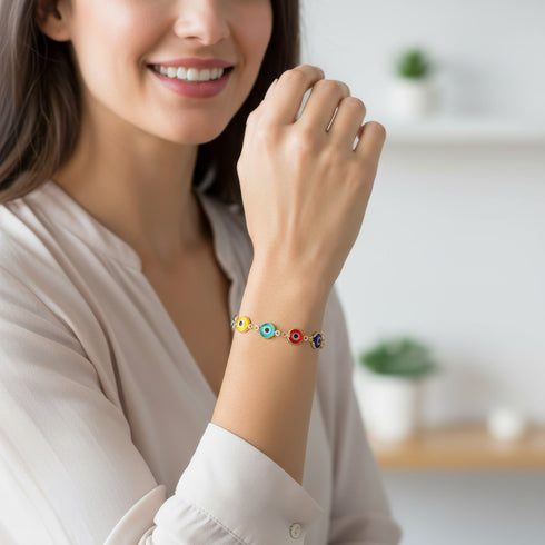 A smiling woman wearing a light blouse shows off her colorful Evil Eye Bracelet, a stylish good luck charm on her wrist.