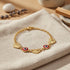 Gold Heart Rolo Link bracelet with red evil eye and heart charms—a protective talisman on a beige fabric background.