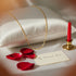 A 14k gold filled mariner link necklace on a white pillow, with rose petals, a red candle, and a “My Dearest Love” card nearby.