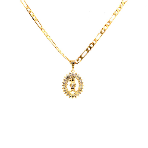 A Little Boy Necklace, perfect for Mother's Day, features a gold-filled Figaro link chain and an ornate oval pendant. Embellished with small gemstones, the pendant depicts a figure holding a staff and offers an elegant touch with its polished rectangular and oval links.
