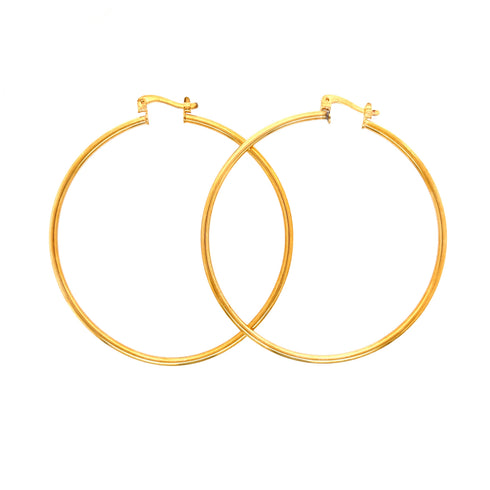 A pair of Big 5.4 cm Hoop Earrings in 14k gold-filled with a thickness of 2 mm and simple clasps. These statement pieces elegantly overlap against a plain white background.