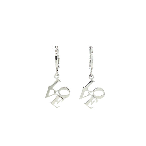 The "Love word Huggie drop earrings," crafted in white gold filled, feature the word "LOVE" in a sleek, modern abstract font. These elegant letters gracefully dangle from small huggie hoops, set against a plain white background that accentuates their stylish design.