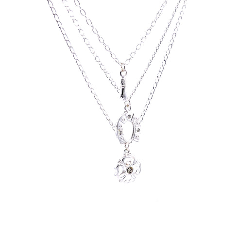 The Good Luck Charms Pendant Stacked Necklace 17 inches Silver Plated boasts three exquisite silver-plated chains adorned with a floral pendant, horseshoe accents, and sparkling rhinestones—each design element symbolizing good fortune against a pristine backdrop.