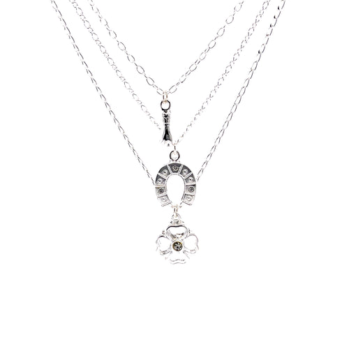 Introducing the Good Luck Charms Pendant Stacked Necklace, 17 inches of silver-plated elegance. This exquisite piece features three delicate chains: the top chain is adorned with an elongated teardrop, the middle showcases a charming horseshoe, and the bottom presents a four-leaf clover charm—all beautifully highlighted against a pristine white background for those seeking a stylish touch of good fortune.