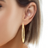 A close-up shot highlights a person wearing the Huge 6 cm Wire Textured Hoops, crafted with 14k gold-filled material. These elegant earrings gracefully hang from the ear, perfectly complemented by their short, light brown hair and skin tone in focus. Designed for comfort, these chic hoops are both lead and nickel-free.