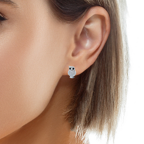 Close-up image of a person wearing cute owl zirconia stones stud earrings in one ear. The earrings are white gold filled, adding a touch of sparkle. The person's hair is short and light brown.