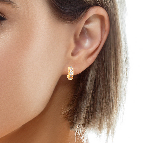 Close-up of a person wearing Tiny Zirconia Stones Huggies Earrings in rose gold filled, showcasing their small hoop design adorned with tiny zirconia stones. The image includes part of the ear and short brown hair, emphasizing these hypoallergenic earrings.