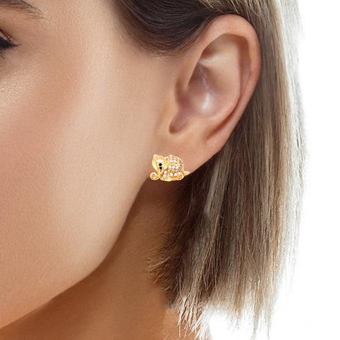 A close-up shot captures a person's ear adorned with the Elephant made of Zirconia Stones Huggie Earring in rose gold, featuring an intricate elephant design with a detailed trunk and large ears. The short brown hair partially veils the ear, accentuating the earring's sparkling zirconia embellishments.