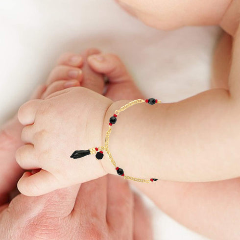 A baby wearing the Genuine Jet Black Azabache Bracelet and Necklace for Evil Eye, exuding the charm of spiritual protection, gently holds an adult's hand.