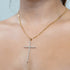 A person wearing the Large Iced Crucifix Pendant Necklace with Figaro Link, featuring a 14k gold-filled chain adorned with sparkling zirconia stones. The neutral background highlights the elegance of this jewelry piece.