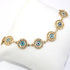 This Blue Turkish Evil Eye Bracelet for Women - Good Luck Charm features 14k gold-filled circular charms with blue and white evil eye designs, stylishly arranged on a white cushion background. It's lead and nickel-free, offering both elegance and peace of mind.